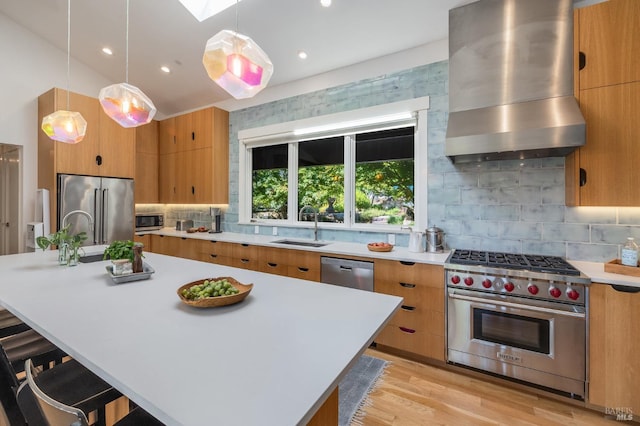 kitchen with a kitchen breakfast bar, hanging light fixtures, wall chimney range hood, and premium appliances