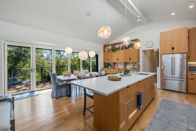 kitchen with sink, stainless steel built in refrigerator, an island with sink, pendant lighting, and light hardwood / wood-style floors