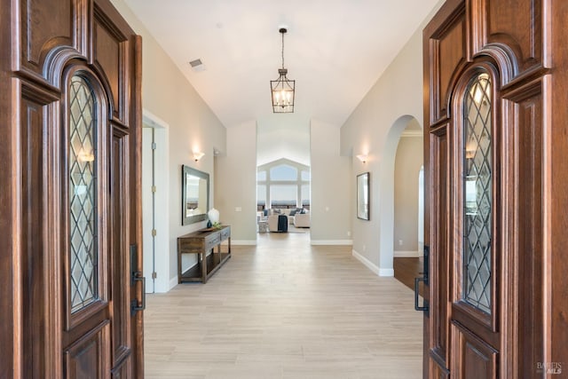 entrance foyer featuring an inviting chandelier, lofted ceiling, and light hardwood / wood-style flooring