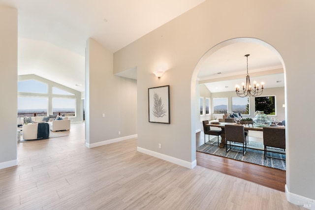 interior space featuring vaulted ceiling, light wood-type flooring, a wealth of natural light, and an inviting chandelier