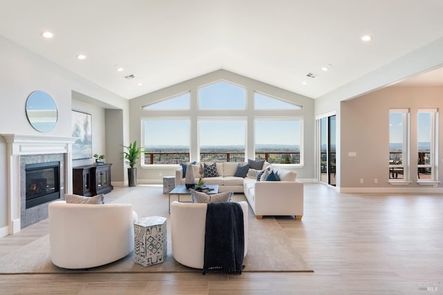 living room with a fireplace, light hardwood / wood-style flooring, a wealth of natural light, and lofted ceiling