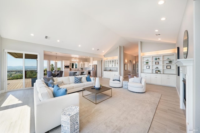 living room featuring an inviting chandelier, lofted ceiling, and light wood-type flooring