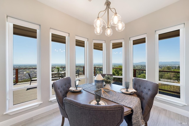 dining space with light hardwood / wood-style floors, a wealth of natural light, and a notable chandelier