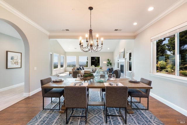 dining area featuring an inviting chandelier, wood-type flooring, crown molding, and vaulted ceiling