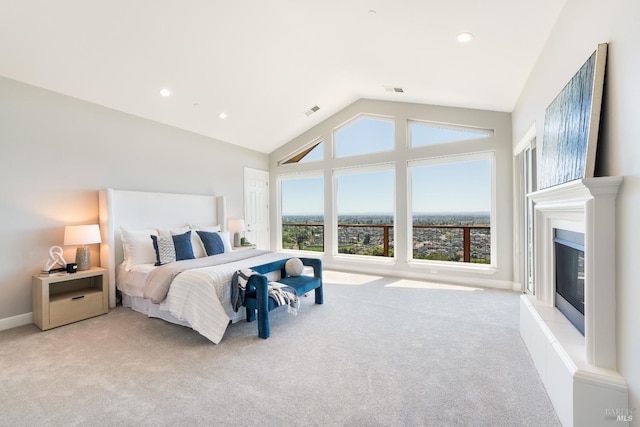 bedroom featuring vaulted ceiling, light carpet, and a tiled fireplace