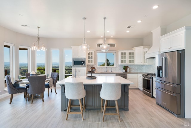 kitchen featuring a kitchen island with sink, white cabinets, and stainless steel appliances