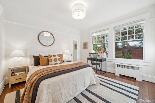 bedroom with radiator heating unit and dark hardwood / wood-style flooring