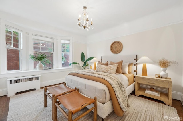 bedroom with radiator heating unit, an inviting chandelier, hardwood / wood-style floors, and multiple windows