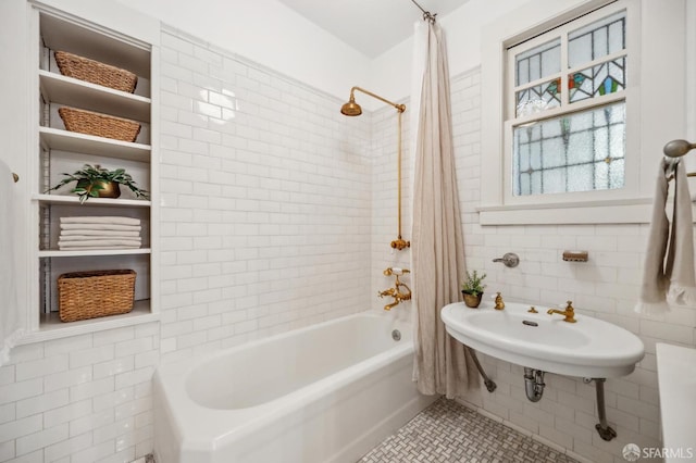 bathroom with tile patterned floors, tile walls, shower / bath combo, and sink