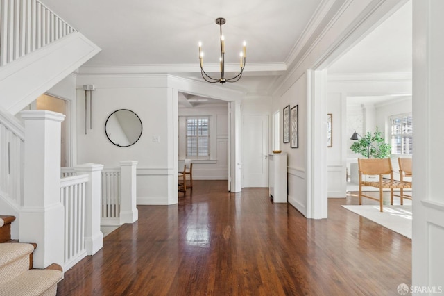 foyer entrance with a chandelier, crown molding, and dark wood-type flooring