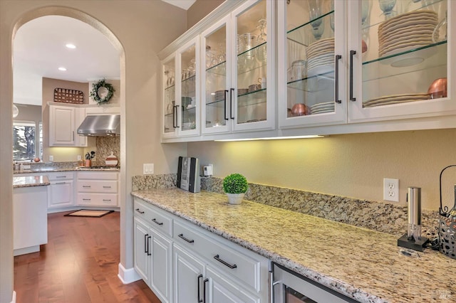 kitchen with white cabinets, wood-type flooring, light stone countertops, and stainless steel gas stovetop