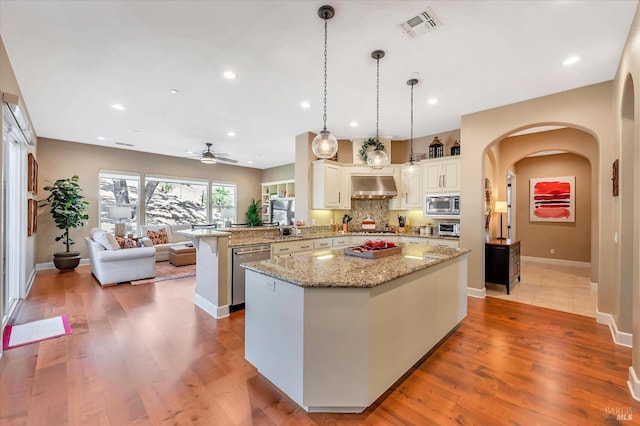 kitchen featuring decorative light fixtures, ceiling fan, a center island, kitchen peninsula, and appliances with stainless steel finishes