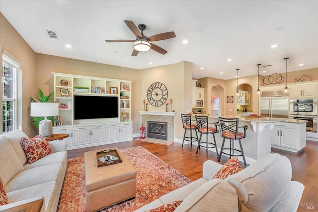 living room with ceiling fan, a fireplace, and dark hardwood / wood-style flooring