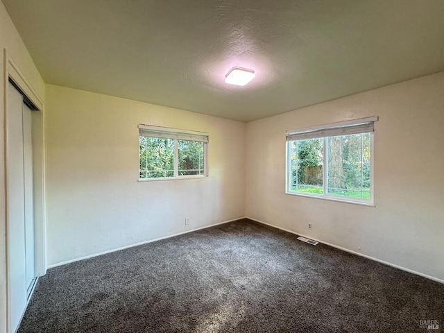 carpeted empty room with plenty of natural light and a textured ceiling