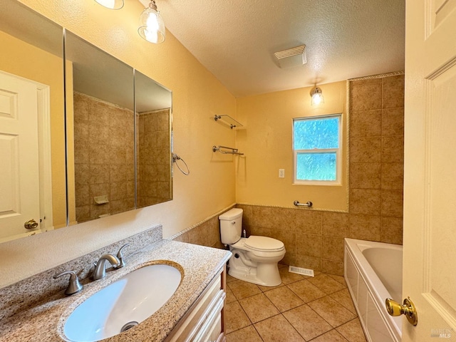 bathroom with vanity, a textured ceiling, tile walls, tile patterned flooring, and toilet