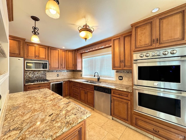 kitchen with sink, stainless steel appliances, light stone counters, pendant lighting, and light tile patterned floors