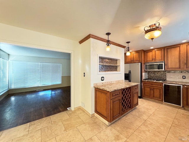 kitchen with tasteful backsplash, light stone counters, a wealth of natural light, stainless steel appliances, and decorative light fixtures