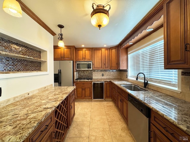 kitchen with light stone counters, sink, stainless steel appliances, and decorative light fixtures