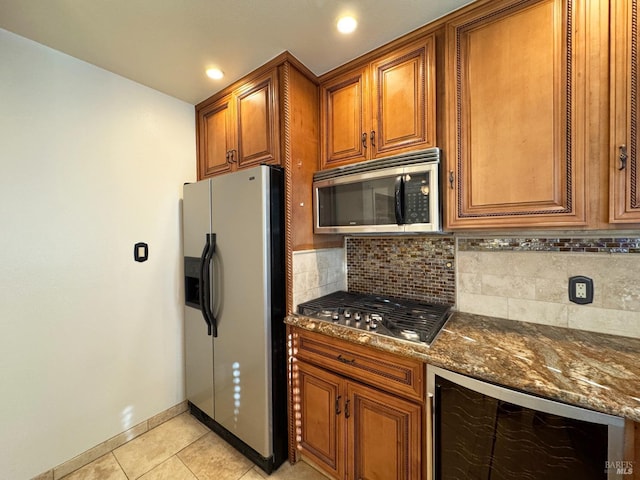 kitchen with beverage cooler, stainless steel appliances, backsplash, dark stone countertops, and light tile patterned floors