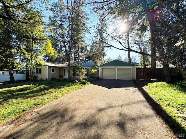 ranch-style home featuring a garage, an outbuilding, and a front lawn