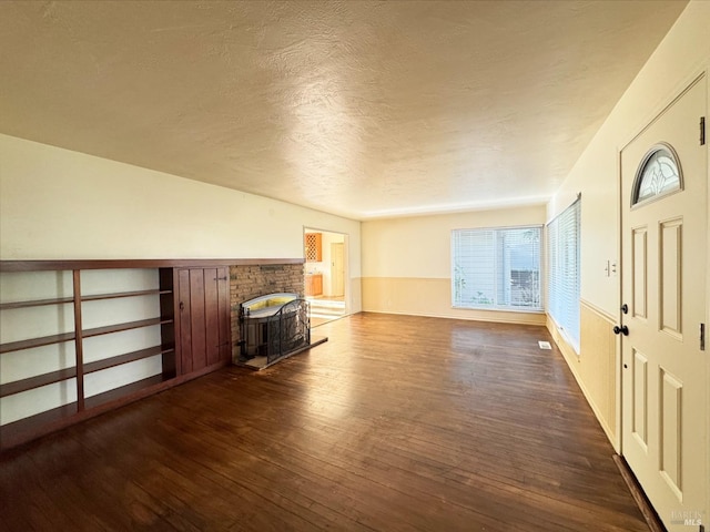 unfurnished living room featuring a textured ceiling and dark wood-type flooring