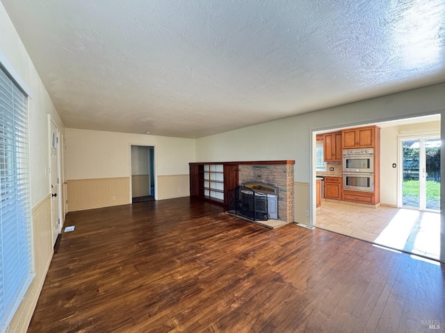 unfurnished living room with a wood stove, a textured ceiling, and hardwood / wood-style flooring