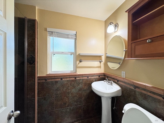 bathroom with sink, toilet, and tile walls