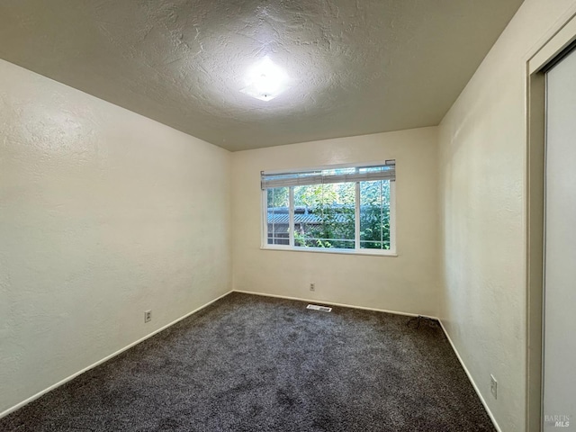 empty room with carpet and a textured ceiling