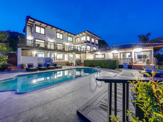 pool at twilight with a patio area