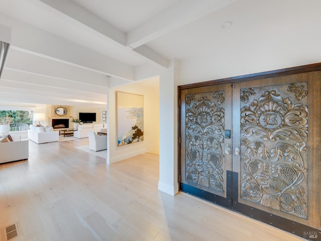 foyer featuring beam ceiling and light wood-type flooring