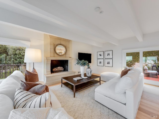 living room with beam ceiling, a large fireplace, and light hardwood / wood-style floors