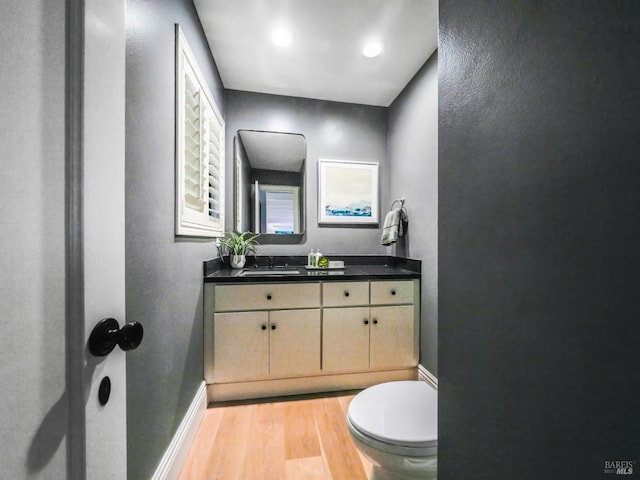 bathroom with toilet, vanity, and hardwood / wood-style flooring