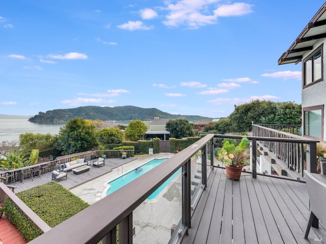 wooden deck featuring outdoor lounge area, a fenced in pool, and a water and mountain view