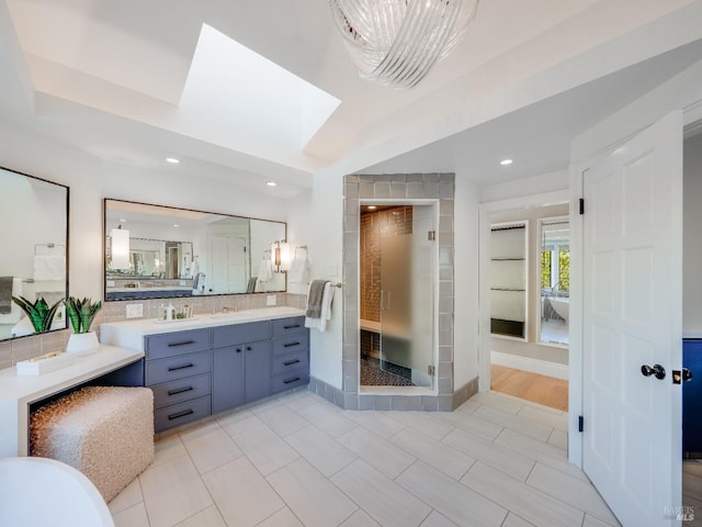 bathroom featuring tasteful backsplash, a skylight, tile patterned floors, an enclosed shower, and vanity