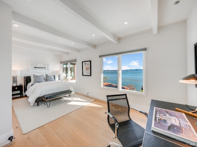 bedroom with beam ceiling, a water view, and wood-type flooring