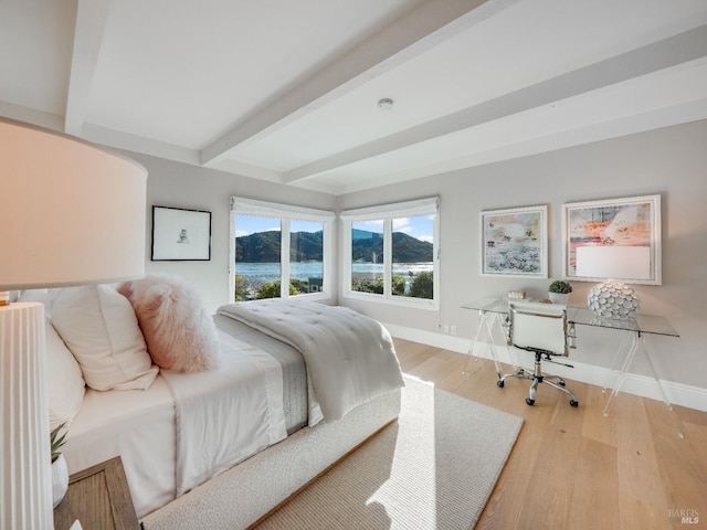 bedroom with a water view, beamed ceiling, and light wood-type flooring