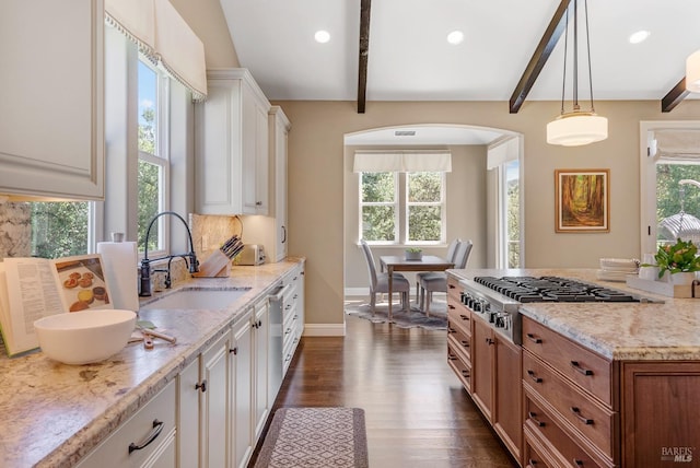 kitchen with sink, hanging light fixtures, beam ceiling, light stone countertops, and white cabinets