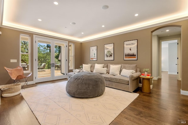 living room featuring hardwood / wood-style floors, a tray ceiling, and french doors