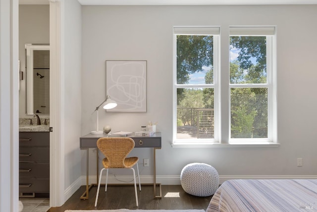 bedroom featuring multiple windows, connected bathroom, sink, and dark wood-type flooring