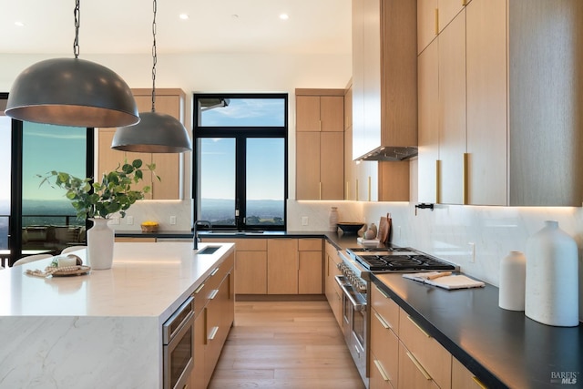 kitchen featuring pendant lighting, a wealth of natural light, light brown cabinets, and stainless steel appliances