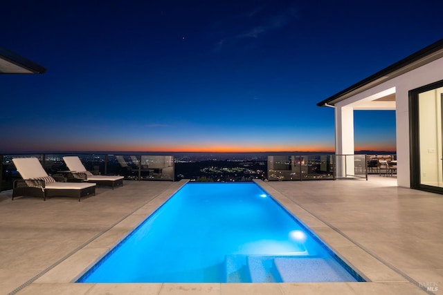 pool at dusk with a patio area