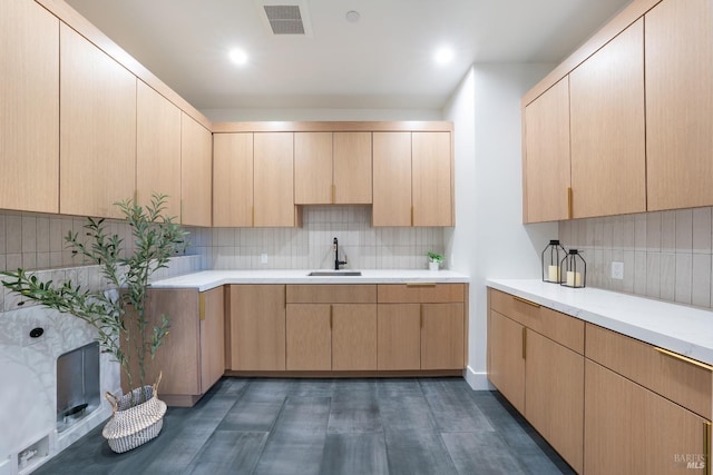 kitchen with backsplash, a fireplace, sink, and light brown cabinetry