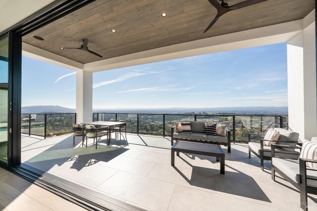 view of patio featuring ceiling fan, a balcony, and a mountain view