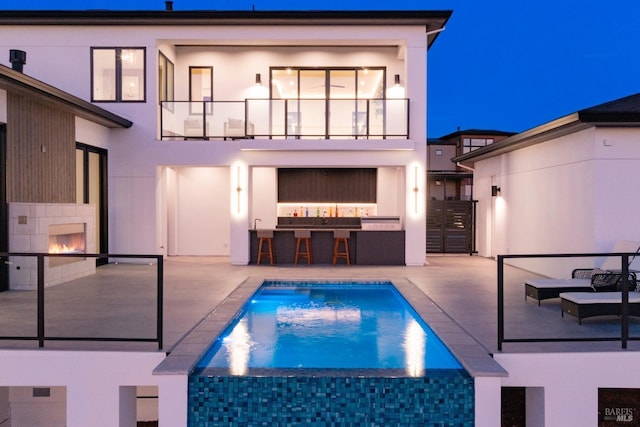 view of pool with an outdoor bar, an outdoor fireplace, and a patio