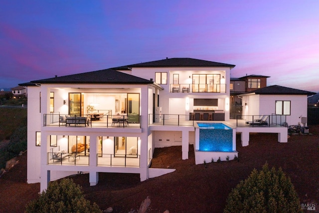 back house at dusk with a balcony