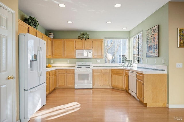 kitchen with light brown cabinets, white appliances, and light hardwood / wood-style floors