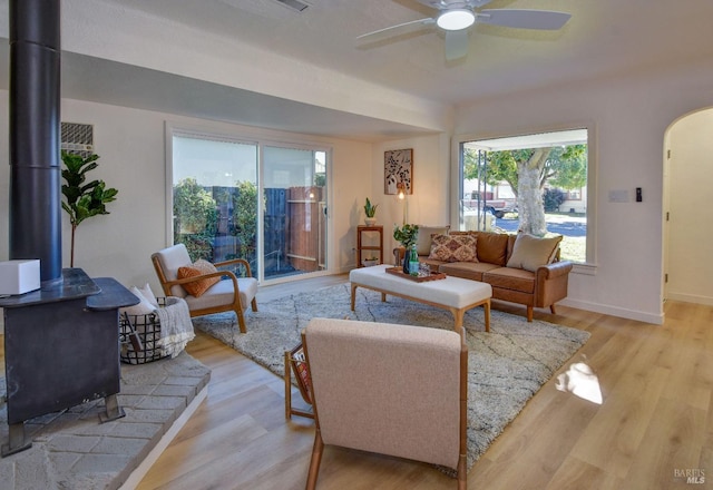 living room featuring ceiling fan, light wood-type flooring, and a wood stove