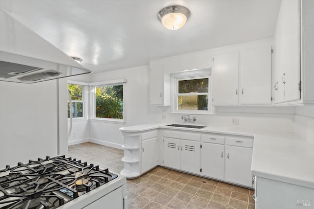 kitchen featuring white cabinets, gas stove, island exhaust hood, and sink