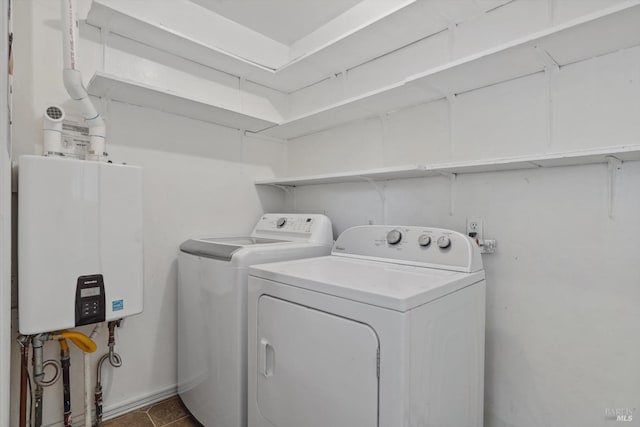 washroom with tankless water heater, dark tile patterned flooring, and washer and clothes dryer