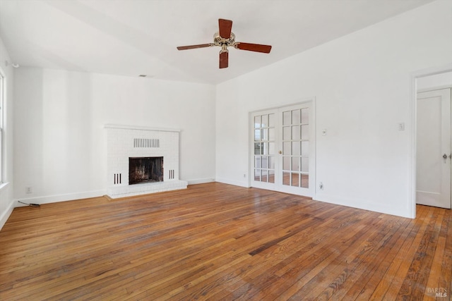 unfurnished living room featuring ceiling fan, wood-type flooring, and a brick fireplace